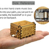 A small, rectangular wooden music box with intricate carvings is held in a person's palm.