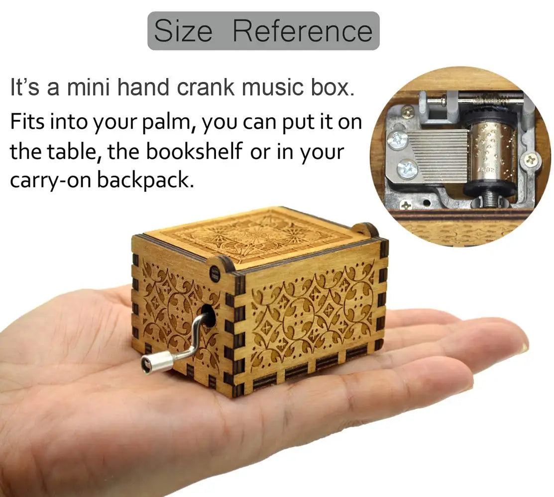 A small, rectangular wooden music box with intricate carvings is held in a person's palm.