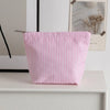 Pochette en crochet rayée rose et blanc posée sur une étagère blanche à côté d'un cadre photo.