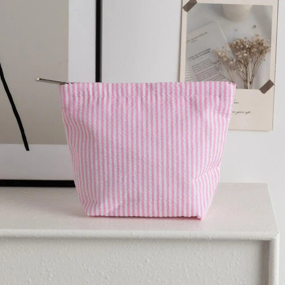 Pochette en crochet rayée rose et blanc posée sur une étagère blanche à côté d'un cadre photo.