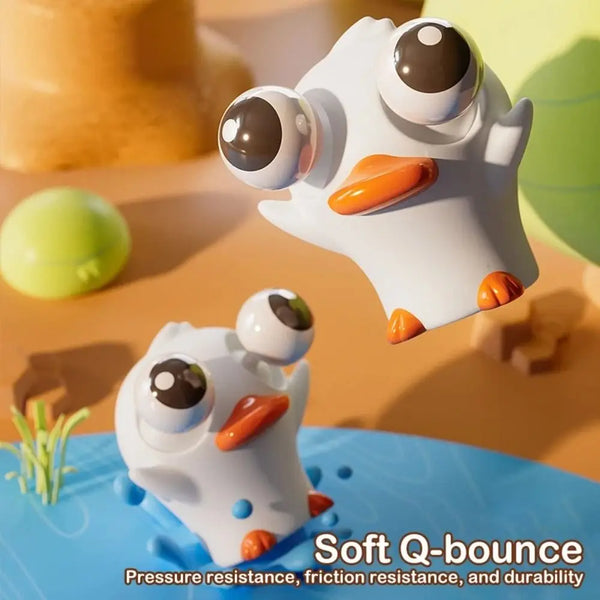 Jouet squishy blanc en forme de hibou avec de grands yeux et un bec orange, posé sur une surface bleue.