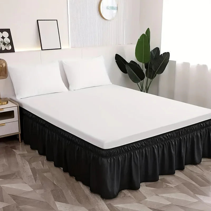 Un lit blanc avec une jupe élastique anti-poussière noire dans une chambre moderne.