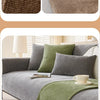 A gray sofa is covered with a solid olive green chenille non-slip protective layer and pillows.