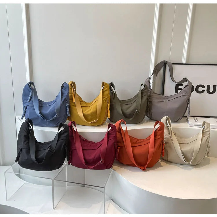 A display of various lightweight nylon crossbody bags in shades of blue, yellow, olive green, gray, maroon, orange, and beige