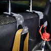 A close-up of a car seat storage hook set with crystal diamond accents mounted on a black fabric surface.