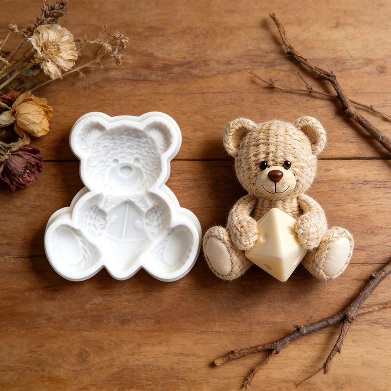 A small, light beige crochet texture teddy bear is positioned next to a white silicone mold on a wooden surface.