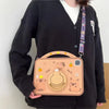 A light brown silicone case featuring a cute cartoon capybara design for an iPad, held by a person wearing a black cardigan.