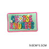 A pink embroidered patch with green lettering that reads Choose Kindness and features small yellow flowers.