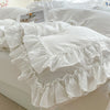 White ruffled duvet cover set with matching pillowcases displayed on a bed.
