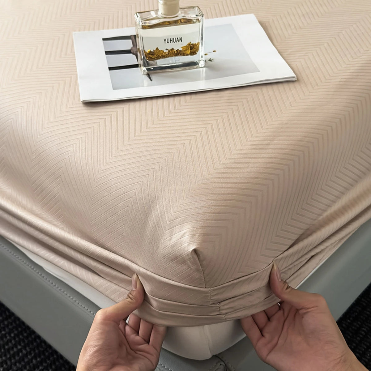 A fitted sheet is folded on a table, displaying a glass bottle of Yuhan product.