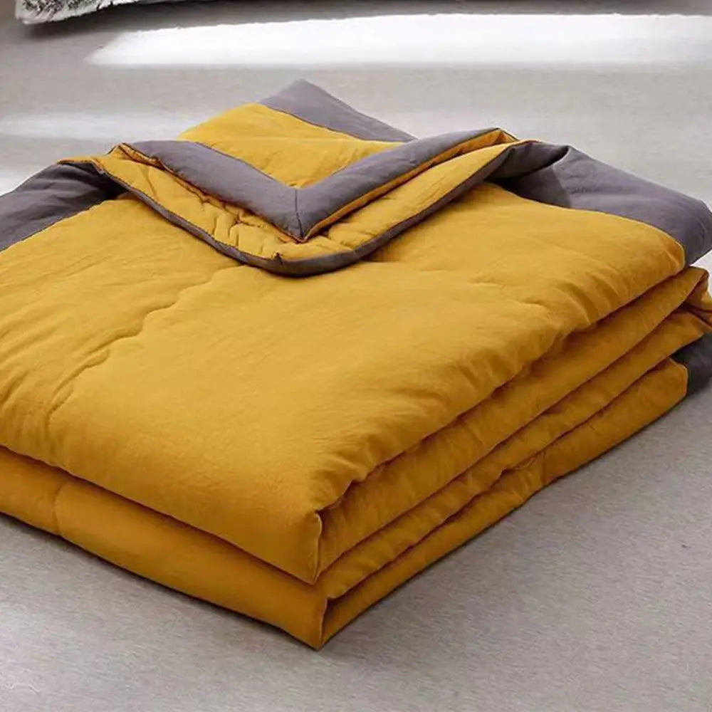 A stack of yellow and gray double-sided cooling blankets folded on a light surface.