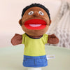 A brown plush hand puppet with large eyes and an open red mouth wearing a lime green shirt and blue shorts.