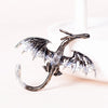 Silver enamel dragon brooch with rhinestone accents displayed on a white surface.