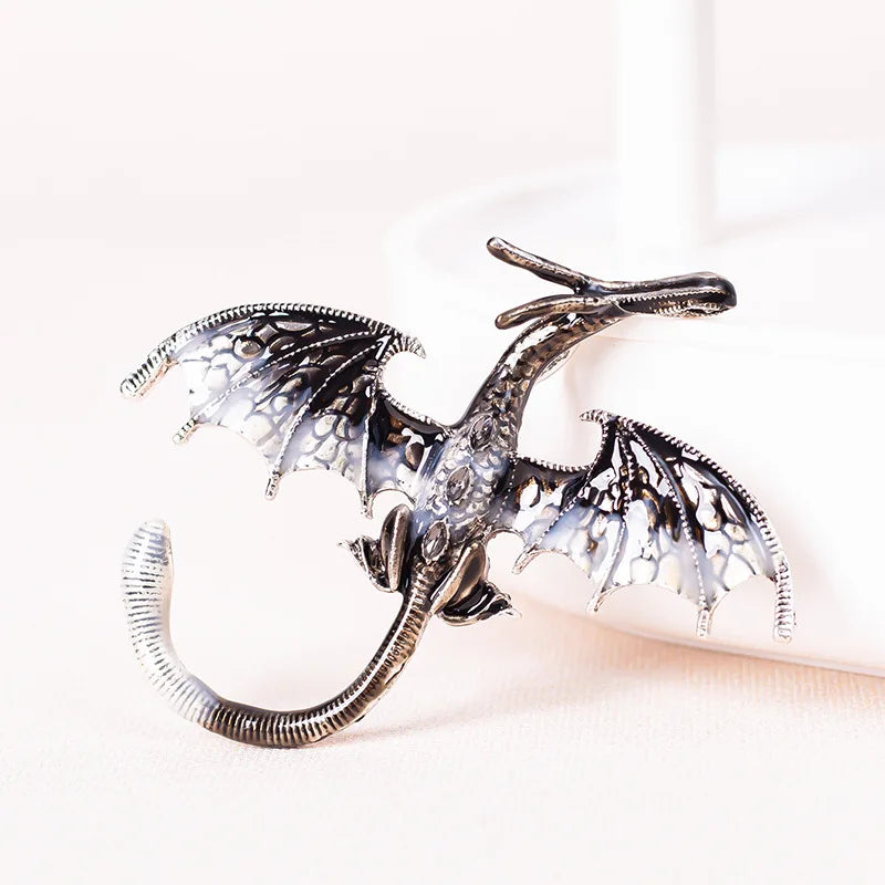 Silver enamel dragon brooch with rhinestone accents displayed on a white surface.