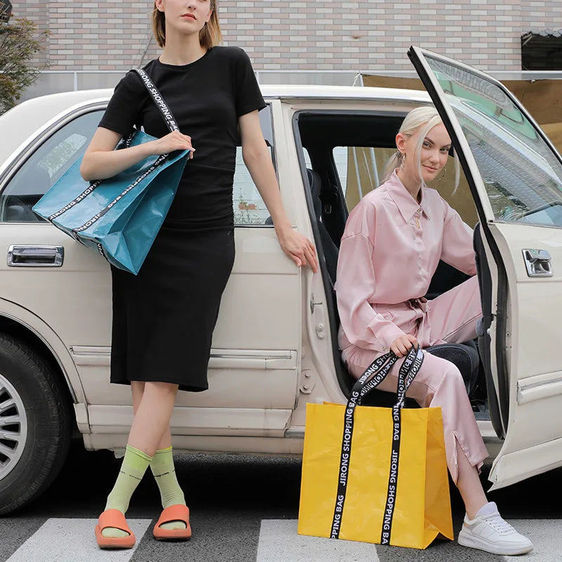 A woman in a black dress holds a blue shopping bag while standing next to a white car with the door open, where another woman