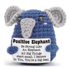A handmade crochet elephant doll in blue and gray with a positive message card attached.