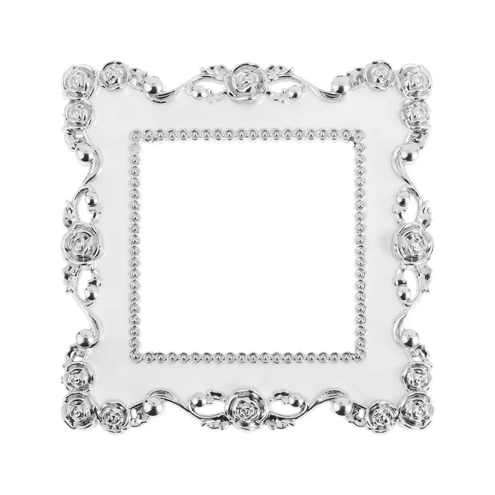 Silver resin light switch cover frame with an ornate, decorative border.