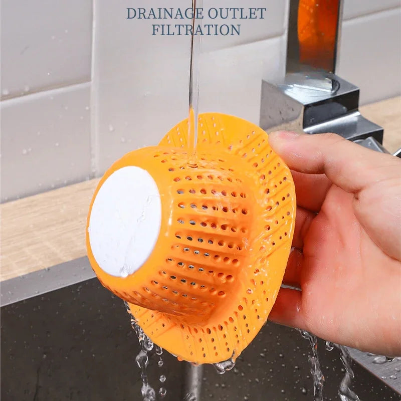 An orange collapsible silicone drain outlet filtration device is shown dripping water into a sink.