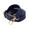 A dark navy blue adjustable leather bag strap replacement coiled and featuring a gold-toned clasp.