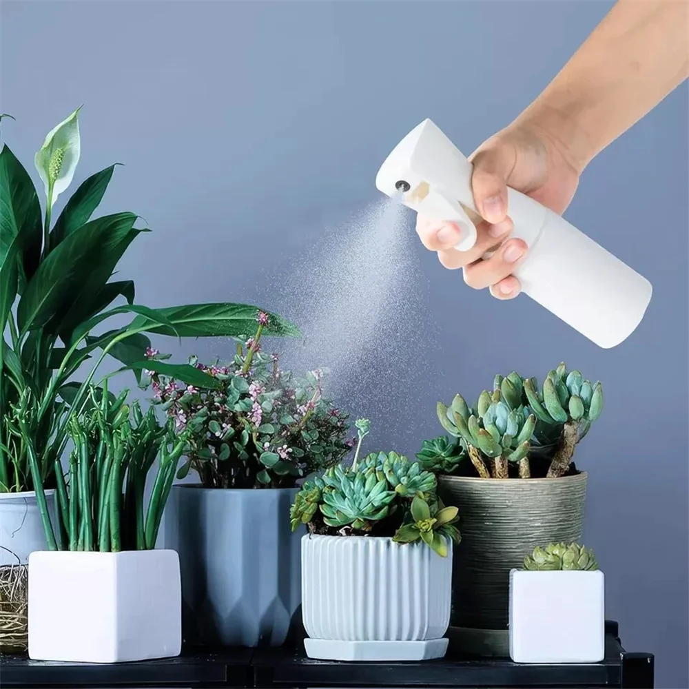 A hand sprays a white mist from a bottle onto green plants and foliage.