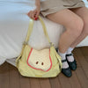 A person wearing a beige skirt is holding a yellow nylon messenger bag.
