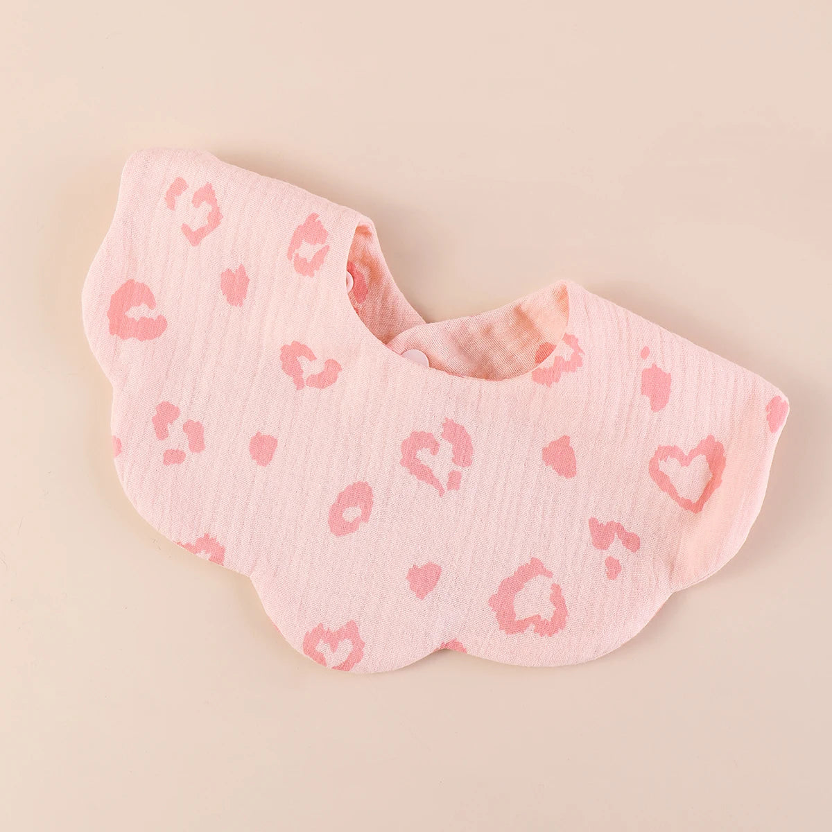 A pink soft cotton baby bib in a bandana style with a leopard print pattern