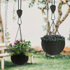 A heavy-duty camping rope tightener with a ratchet lock hanging, holding a woven basket of purple flowers.