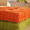 A stack of thick orange and green corduroy floor cushions for meditation and seating.