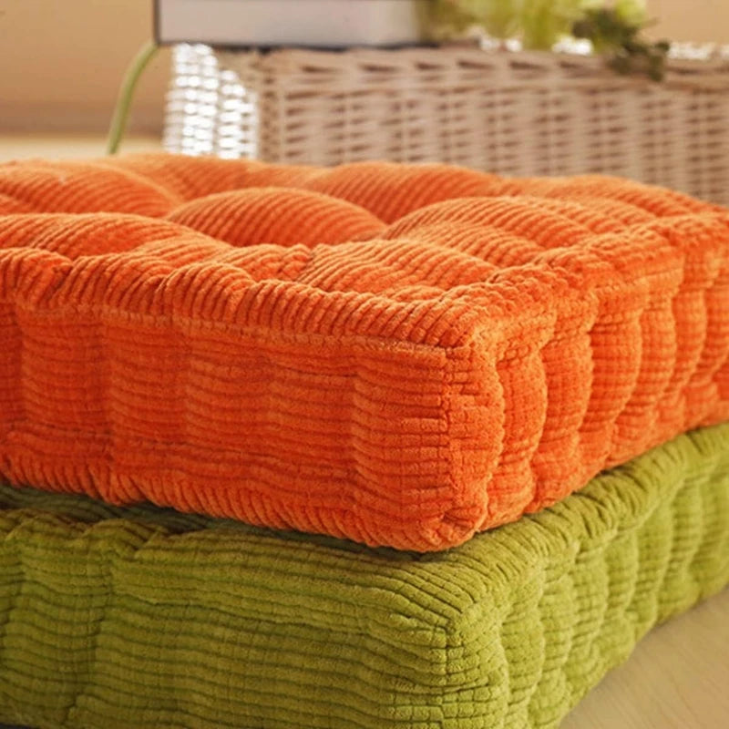 A stack of thick orange and green corduroy floor cushions for meditation and seating.