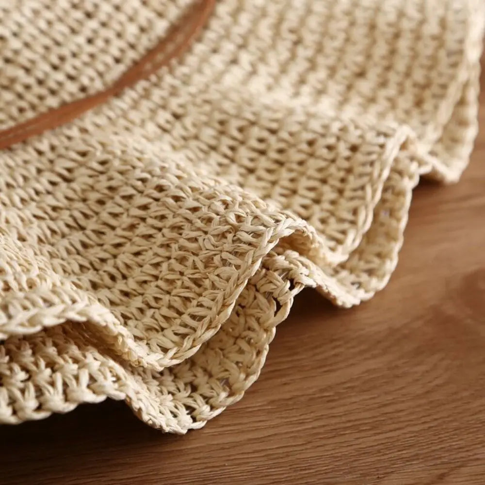 Primer plano de tela de punto beige, posiblemente parte de un sombrero de paja de ala ancha estilo francés.