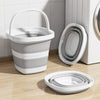 A white collapsible bucket and a white portable toilet are shown on a wooden floor.
