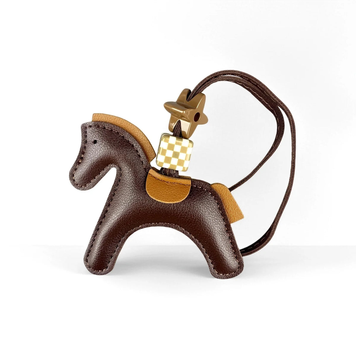 A brown leather pony charm with a gold-toned buckle and checkered tag hanging from a leather strap.