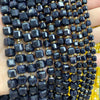 A close-up of dark blue and black square faceted beads strung together on a string.