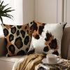 A decorative leopard print pillowcase with brown and black spots resting on a light-colored sofa.
