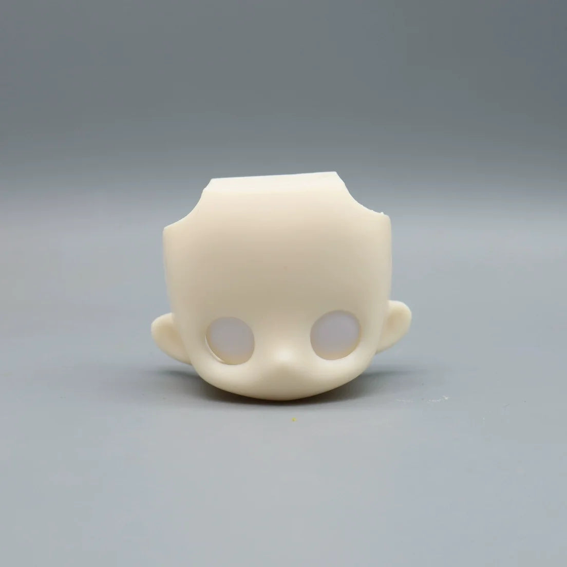 A light beige articulated BJD collectible figurine with a smooth, rounded head and visible eye sockets.