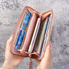 A pink leather wallet with multiple card slots is held open, showing various cards inside.