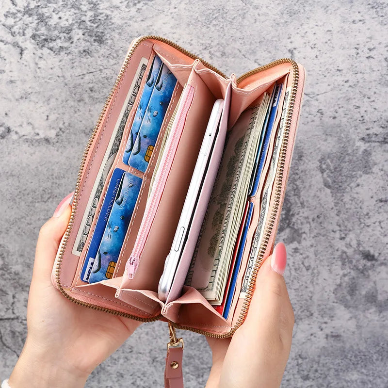 A pink leather wallet with multiple card slots is held open, showing various cards inside.