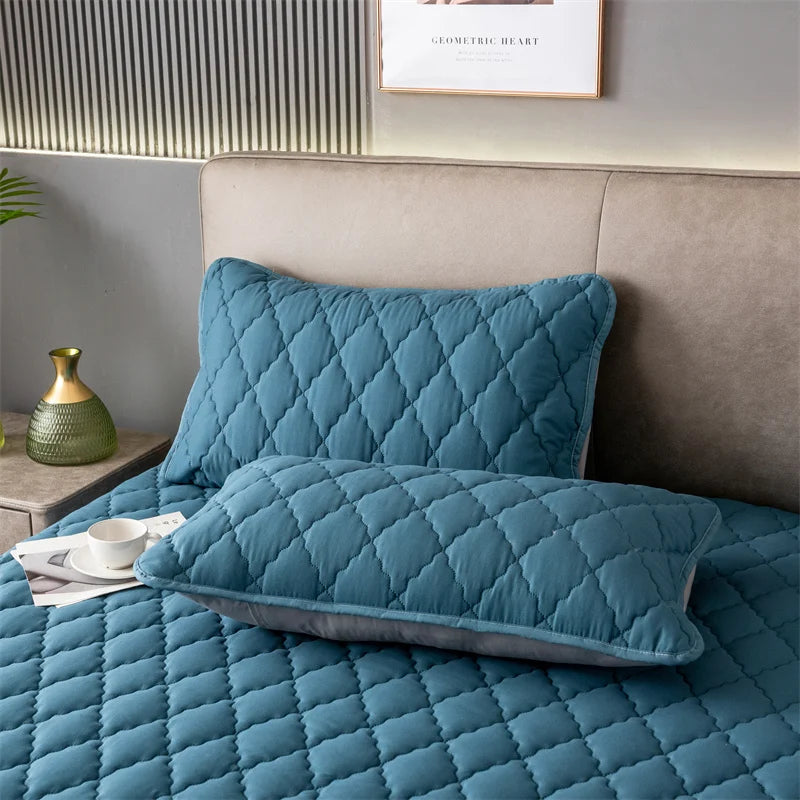 A teal quilted pillow protector resting on a bed, next to a headboard and a small vase.