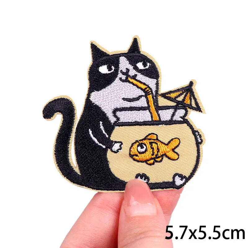 A black and white cartoon cat embroidery patch holding a yellow fish.