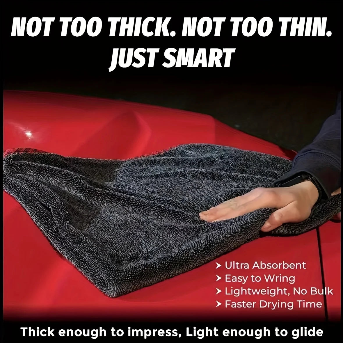 A dark gray microfiber car drying towel is shown draped over a red car surface.