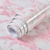 Roll of white marble contact paper with pink veining lying on a pink and white marble surface