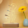 Illuminated acrylic guitar pick holder with a wooden base featuring a guitar silhouette and picks.