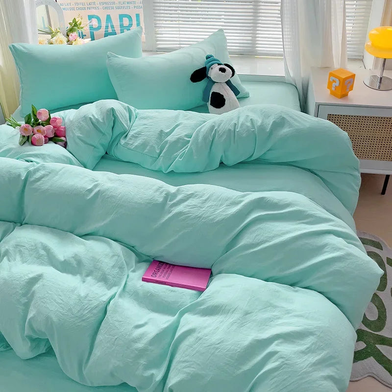 A light aqua bedding set featuring a duvet cover, flat sheet, and pillowcases with a small animal plush toy.