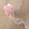 Pink organza ribbon rolled and unwound on a wooden surface