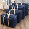 A stack of dark blue waterproof moving and storage bags tied with beige straps on a wooden floor.