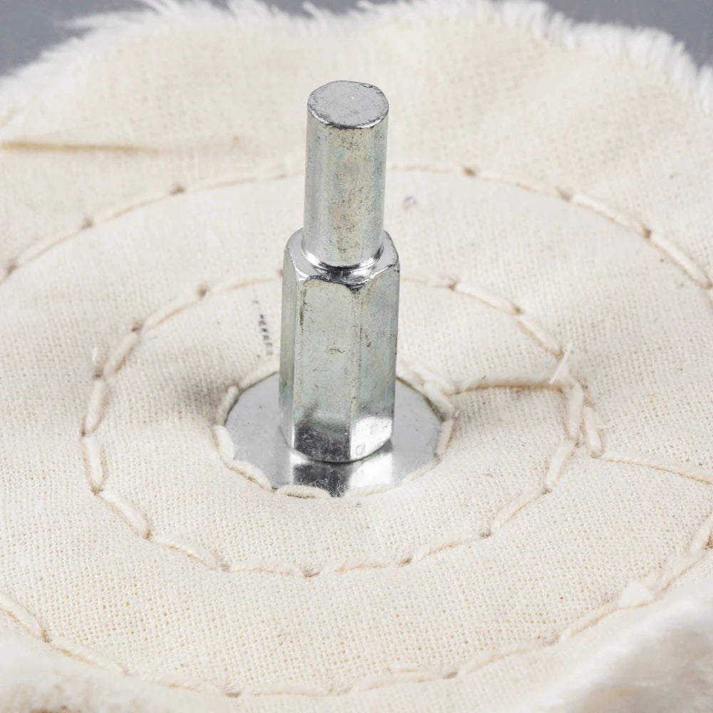 A silver metal polishing buffing wheel with a 1/4 inch shank set against a white cloth background.