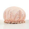 A light pink reusable elastic shower cap with gold heart pattern