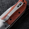 A folding pocket knife featuring a dark walnut wood handle and stainless steel blade, shown in profile.