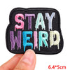 A set of embroidered iron-on letter patches in various colors including pink purple and teal on a black fabric
