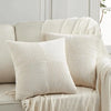Two cream-colored, vertically ribbed patchwork throw pillow covers draped on a light sofa.